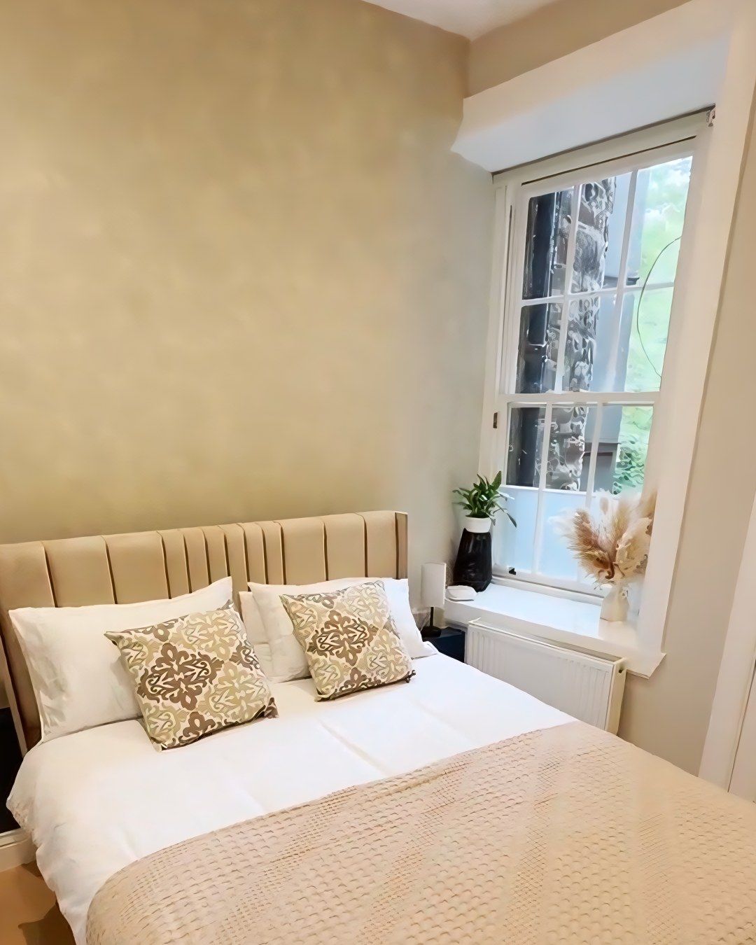 Finished bedroom in the Old Town flat, with a sash window over the stone wall outside