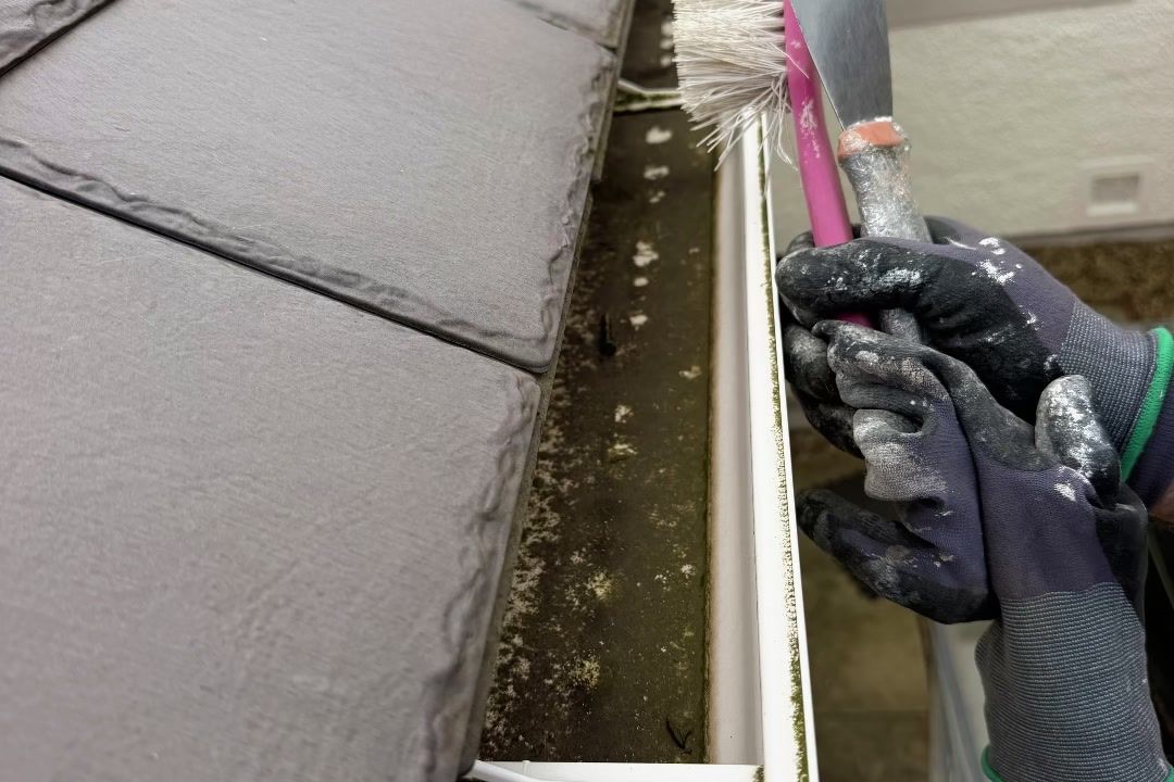 Cleaning out the gutters along the slate roof