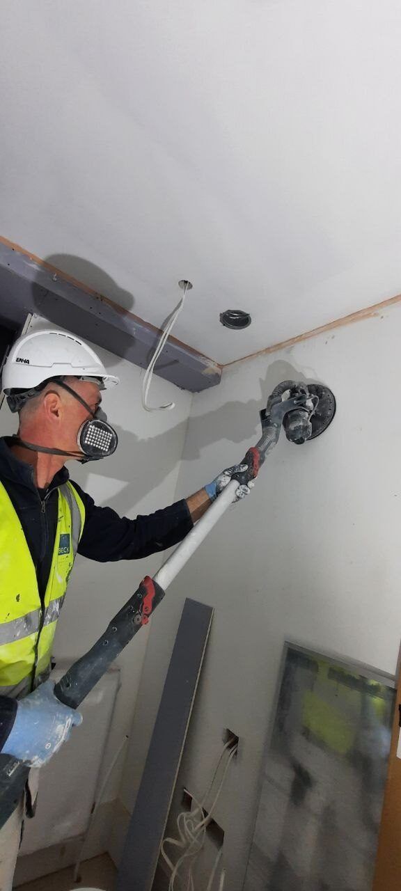 Vitalii sanding a ceiling with a pole sander