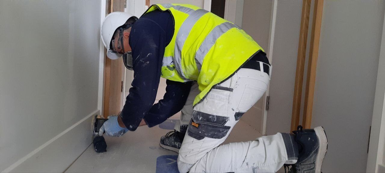 Vitalii sanding a door frame with floor protection laid