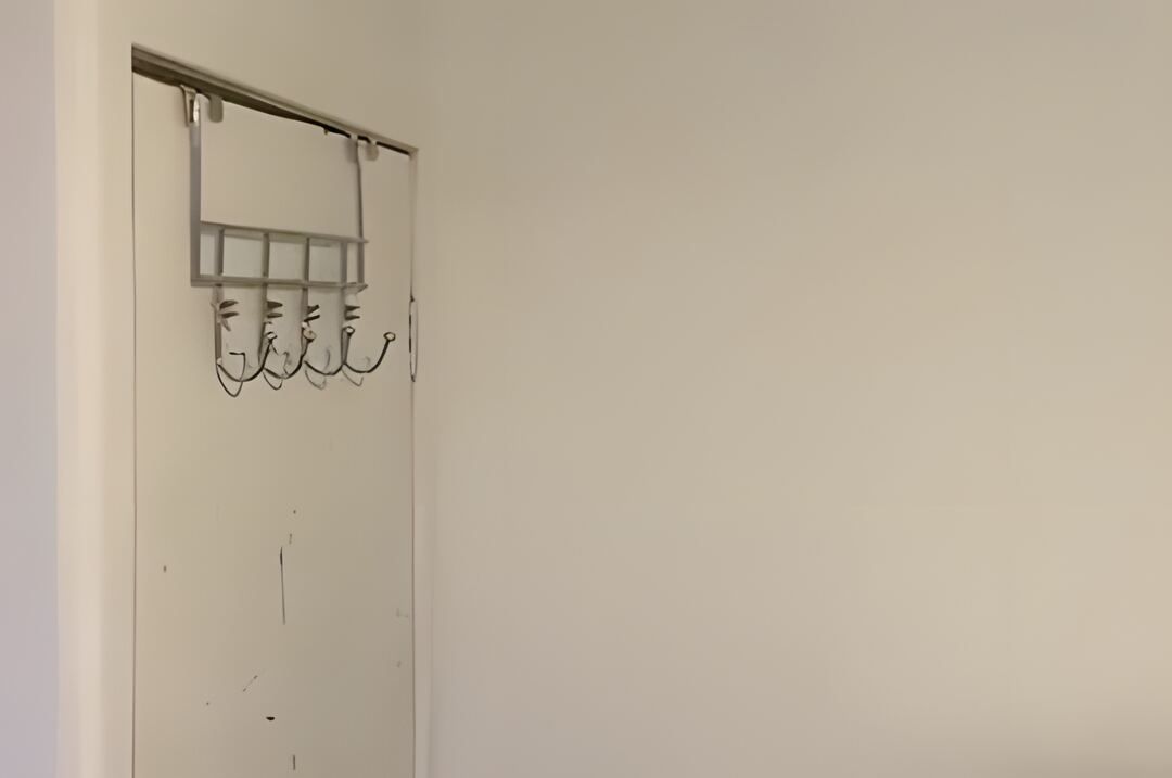 Spare room wall painted white with the coat hooks refitted