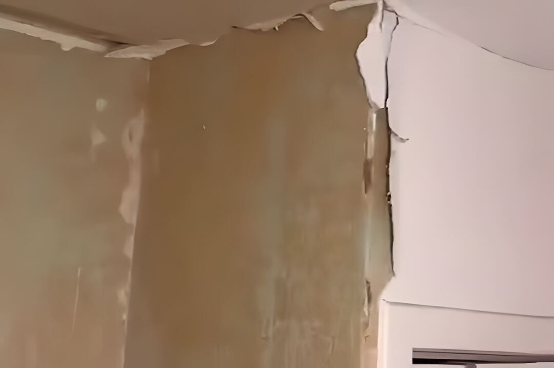 Spare room wall stripped back to bare plaster, ceiling torn