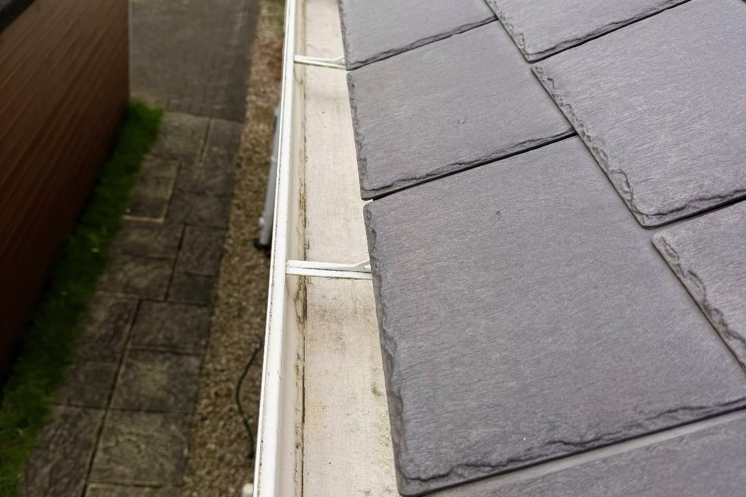 Clear white gutter running along the slate roof