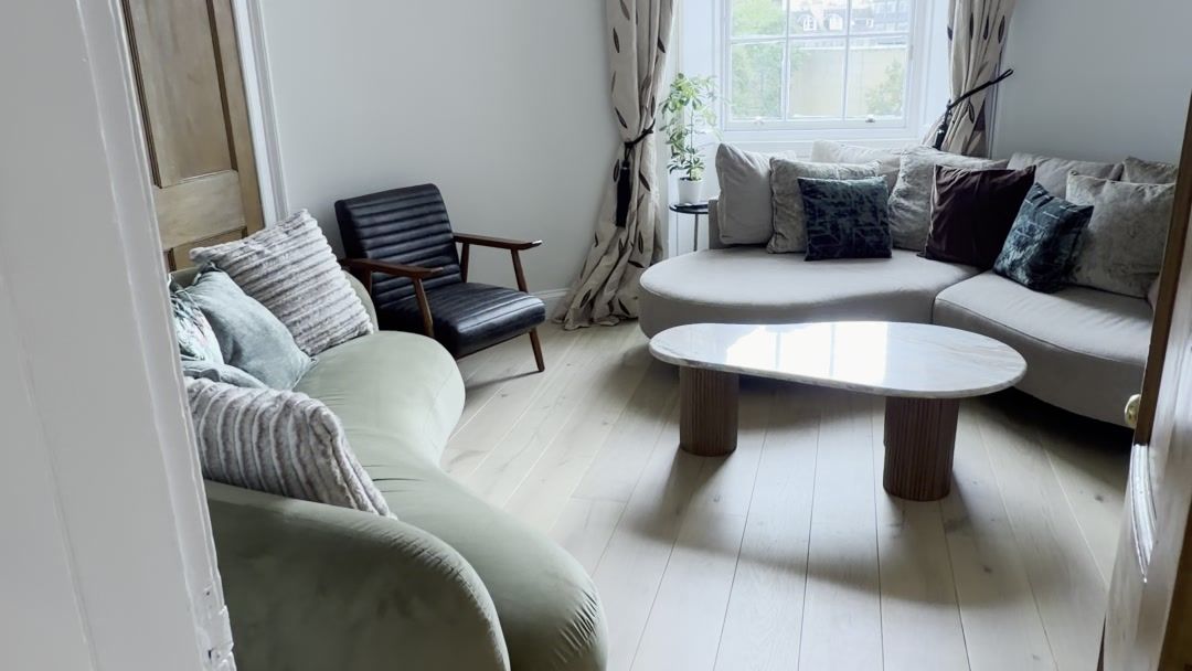 Renovated living room with sofa, armchair and new oak flooring